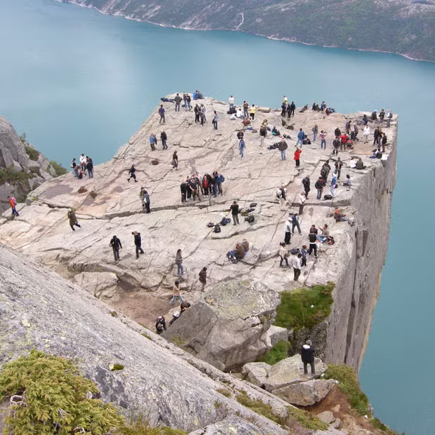 Daredevil tourists dangle their legs over the edge of a dizzying 1,982ft tall cliff face. Brit Greg MacDonald took this picture at Pulpit Rock in Norway. The enormous cliff face attracts hundreds of thousands of thrill seekers each year. Many simply enjoy the stunning view from the plateau but the very brave stand and sit on the edge of the gigantic rock face.