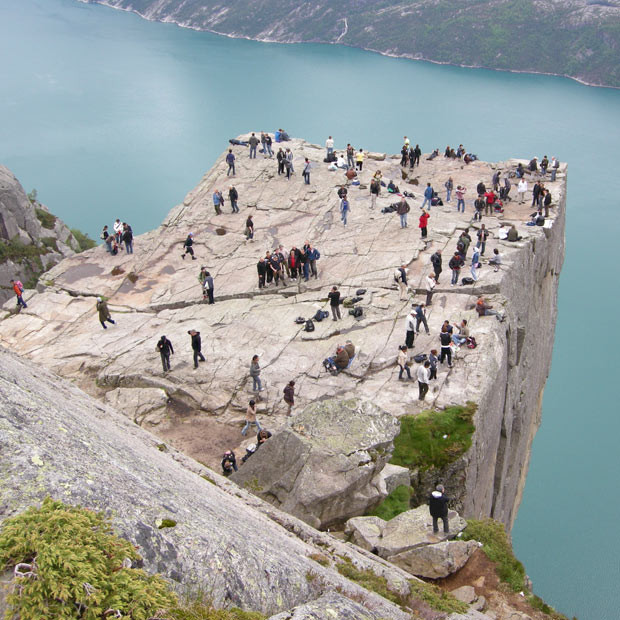 Daredevil tourists dangle their legs over the edge of a dizzying 1,982ft tall cliff face. Brit Greg MacDonald took this picture at Pulpit Rock in Norway. The enormous cliff face attracts hundreds of thousands of thrill seekers each year. Many simply enjoy the stunning view from the plateau but the very brave stand and sit on the edge of the gigantic rock face.