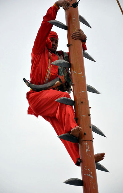 Màn leo cột với những lưỡi dao ở Quảng Tây, Trung Quốc A man climbs up a pole using knife blades as a ladder during the Zhuang ethnic minority games in Nanning, Guangxi Province, China