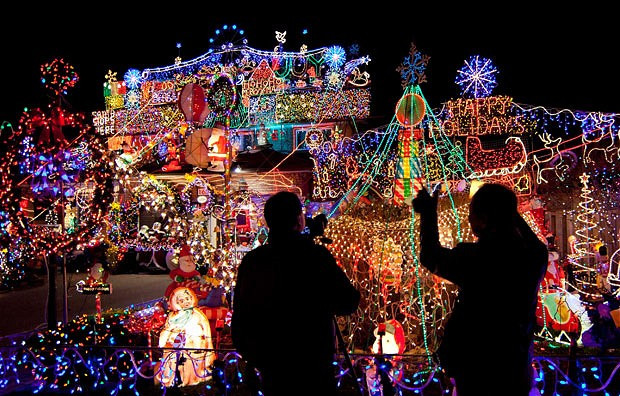 People take photos of colourful Christmas lights in front of a house in Toronto, Canada