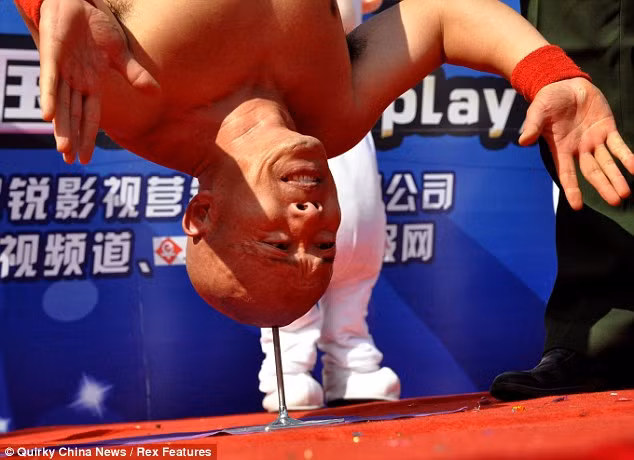 Li Xin balances upside down on a spike at a stunt event in China. The full weight of his 10st7lbs body bears down on the spike, putting intense pressure on his skull Read more: http://www.dailymail.co.uk/news/article-2070586/Stuntman-Li-Xin-balances-nail-head.html#ixzz1fqJoZEcB