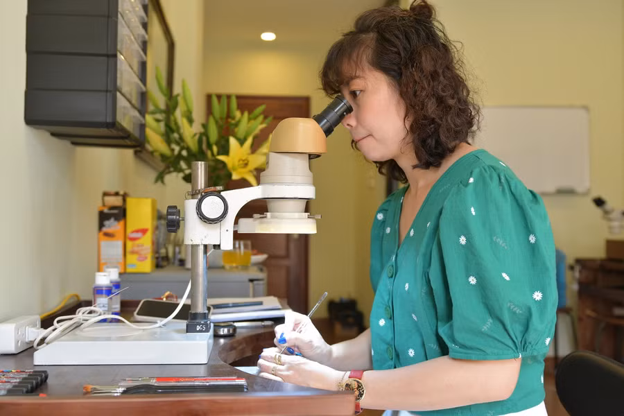 Chị Vũ Thùy Dương tỷ mỷ trong từng chi tiết nhỏ khi làm việc vẽ mặt đồng hồ qua kính hiển vi.