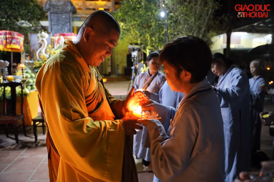 Từ một ngọn nến, các sư thầy chùa Hòa Phúc truyền lửa đến hoa đăng trên tay từng Phật tử.
