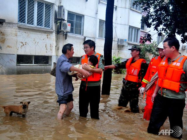 This picture taken on 6 Aug shows rescuers help evacuating a family from their flooded home after a storm following Typhoon Saola hit Shiyan