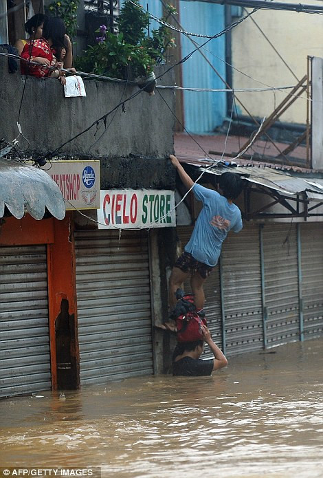 Brave gesture: A man (left) wades up to his waist to bring food and hot drinks to people staying inside their flooded homes in Quezon City, while others (right) climb over a shop to reach their property Read more: http://www.dailymail.co.uk/news/article-2184925/Philippines-floods-Manila-submerged-leaving-9-dead-scores-homeless.html#ixzz22uj2oUWM