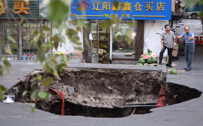 Residents look at a pit caused by a road cave-in, in Harbin, Heilongjiang province, China. According to local authorities, two people died from injuries sustained when they fell into the 10-metre-deep pit...