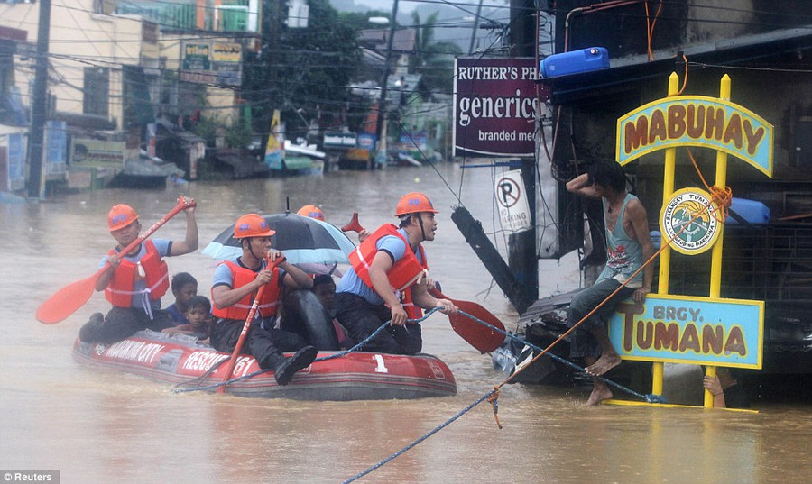 Timely arrival: Rescuers reach a man using a rubber dinghy and paddles as the deadly rains continue Read more: http://www.dailymail.co.uk/news/article-2184925/Philippines-floods-Manila-submerged-leaving-9-dead-scores-homeless.html#ixzz22uiieOQw