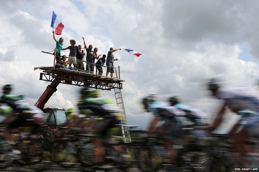 Fans wave French flags as the pack rides in the fifth stage of the 2012 Tour de France cycling race.
