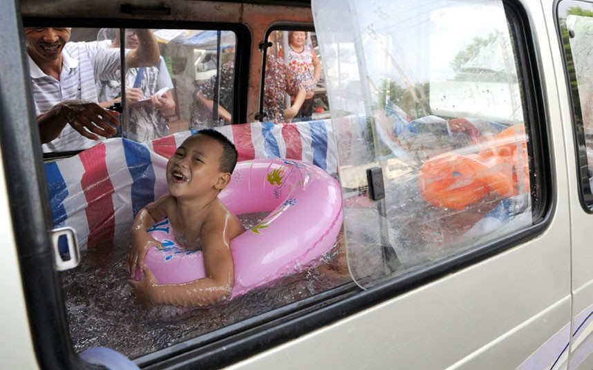 Zhou Yuhang plays in a mobile swimming pool which his father built in the back of a van, in Wenzhou city, Zhejiang province, east China. The child’s father removed the seats of a van and lined it with plastic.