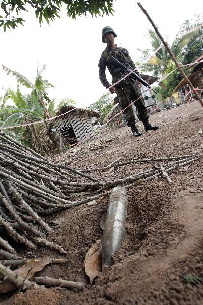 A Thai soldier stands close to an unexploded artillery shell in a village close to the Thai-Cambodia border April 24, 2011 A Thai soldier stands close to an unexploded artillery shell in a village close to the Thai-Cambodia border April 24, 2011