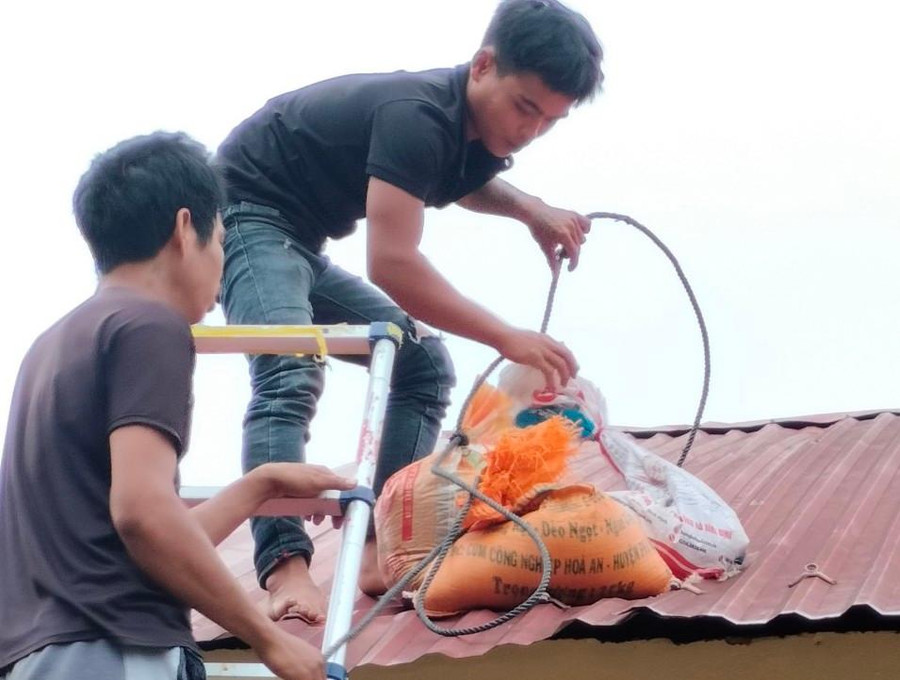 Các bao cát được di chuyển lên mái nhà để chằng chống không cho tốc mái.