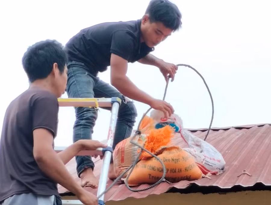Các bao cát được di chuyển lên mái nhà để chằng chống không cho tốc mái.