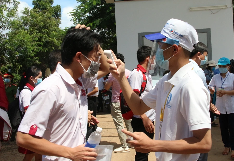 Các em học sinh được đo nhiệt độ, sát khuẩn trước khi vào trường.