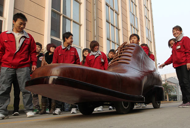 Những hình ảnh ấn tượng trong tuần ảnh 2 A shoe-shaped electric car is put through its ’paces’ as colleagues watch at a shoe factory in Wenzhou, Zhejiang Province, China. It is said that the three-metre-long battery-powered vehicle can travel 400 kilometres on a full charge with speeds of up to 30 kilometres per hour