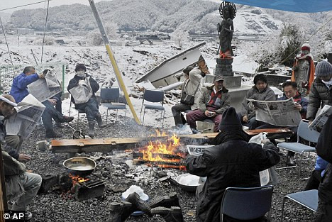 Không nhà ở và chịu sự giá lạnh, những người dân tụ tập lại ở Otsuchi Homeless and freezing, people huddle around a camp fire in Otsuchi Read more: http://www.dailymail.co.uk/news/article-1367019/Desperate-families-left-forage-scraps-snow-worlds-richest-country.html#ixzz1GsV4TKUu