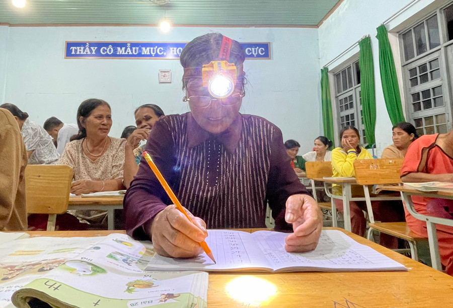 Mắt mờ nên bà Y Mơk phải đội đèn viết chữ. Mắt mờ nên bà Y Mơk phải đội đèn viết chữ.