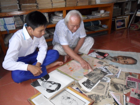 Thầy Đậu Xuân Tiêu đang giới thiệu cho cháu nội (Đậu Minh Đức) về các tư liệu quý về Chủ tịch Hồ Chí Minh.JPG