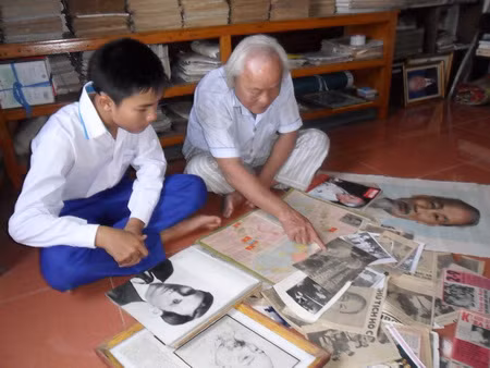 Thầy Đậu Xuân Tiêu đang giới thiệu cho cháu nội (Đậu Minh Đức) về các tư liệu quý về Chủ tịch Hồ Chí Minh.JPG