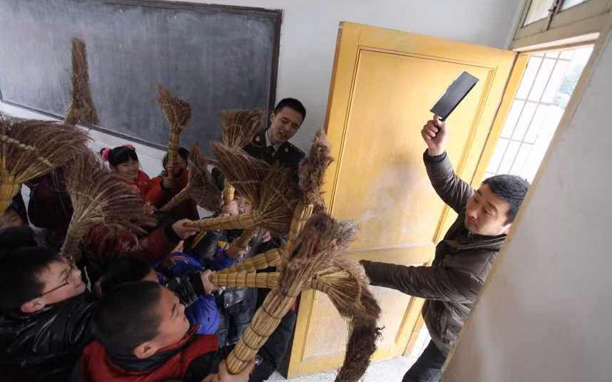 Primary school children practise defending themselves with brooms during an anti-violence exercise at a school in Rugao, Jiangsu province, China