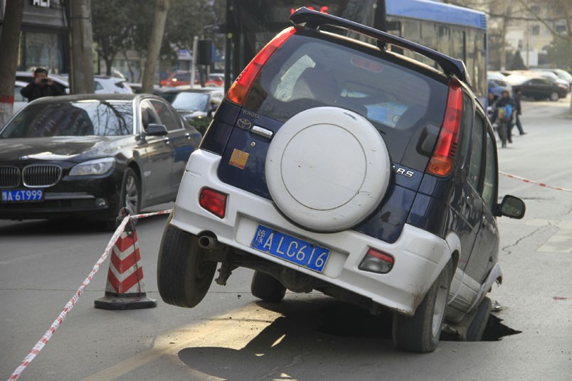 Những hình ảnh ấn tượng trong tuần ảnh 2 A car is trapped in a hole after a road caved in, in Zhengzhou, China