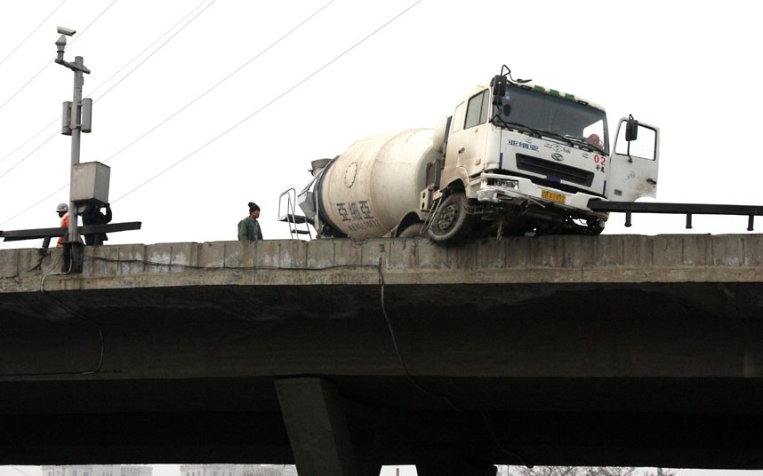 An overloaded cement tanker is seen hanging off a 30m high road flyover after an accident in Dalian, northeast China’s Liaoning Province. According to the driver of the tanker he was forced to take evasive action to avoid hitting a car. The move caused his vehicle to crash into and through the safety fence at the side of the road.