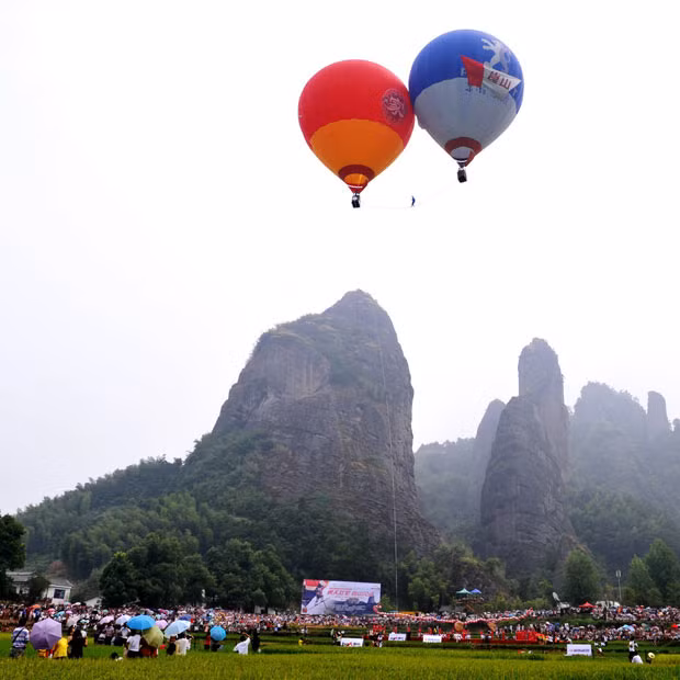 Những hình ảnh ấn tượng tuần qua ảnh 4 A Chinese high-wire artist has secured his fourth Guinness World Record for traversing a wire strung between two floating hot air balloons, in Xinning County, southern China’s Hunan Province. Saimaiti Aishan walked along a 15-metre long steel wire suspended 30 metres above ground between two hot air balloons, taking three minutes and 38 seconds to make the crossing