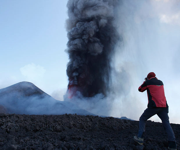 ...A man takes a picture as mount Etna spews volcanic ash during an eruption on the southern Italian island of Sicily. Mount Etna is Europe’s tallest and most active volcano.