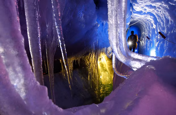 A man with a torch walks in the Natur Eis Palast (Nature Ice Palace) inside the Hintertuxer Glacier in the Austrian province of Tyrol...