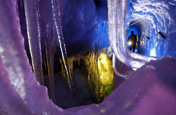 A man with a torch walks in the Natur Eis Palast (Nature Ice Palace) inside the Hintertuxer Glacier in the Austrian province of Tyrol...