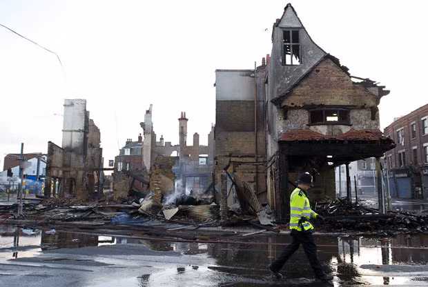 Những hình ảnh ấn tượng tuần qua ảnh 10 A policeman walks past the charred remains of the Reeves furniture store in Croydon, south of London