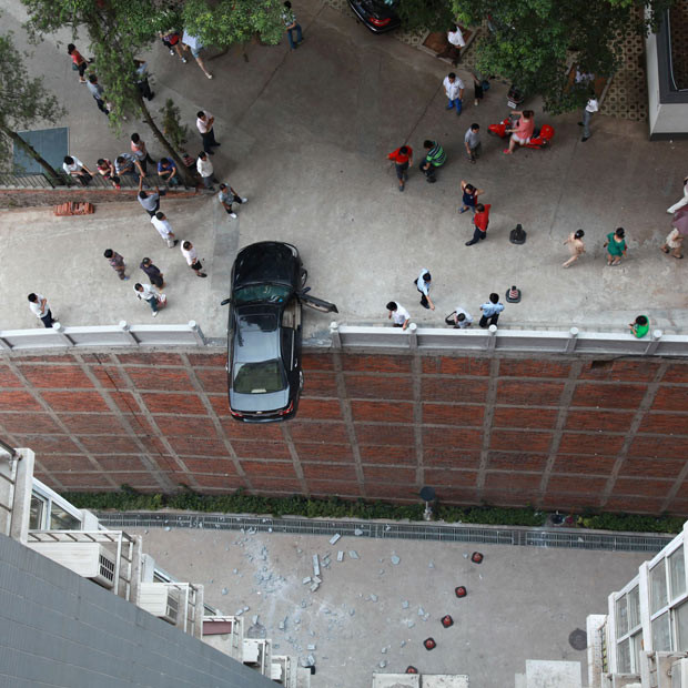 Chùm ảnh: Những "điểm đậu" hy hữu của xe hơi ảnh 1 A couple had a very lucky escape after nearly reversing their car off a 15m drop in Changsha, capital of southern China’s Hunan Province. The man and woman were parked on the top of a car park when the incident happened. It is thought that whoever was driving mistakenly trod on the accelerator, causing the car to reverse. This sent it smashing through the wall around the edge of the car park and left the vehicle teetering precariously over the 15m drop below. The couple were forced to crawl carefully out from the vehicle and were luckily uninjured.