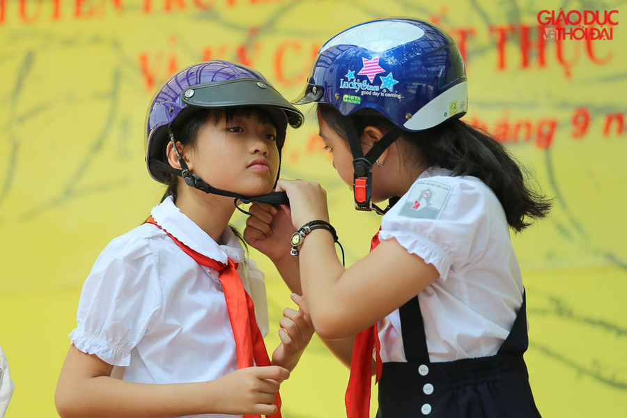 Học sinh tiểu học thực hành đội mũ bảo hiểm đúng cách cho mình và cho bạn khác.
