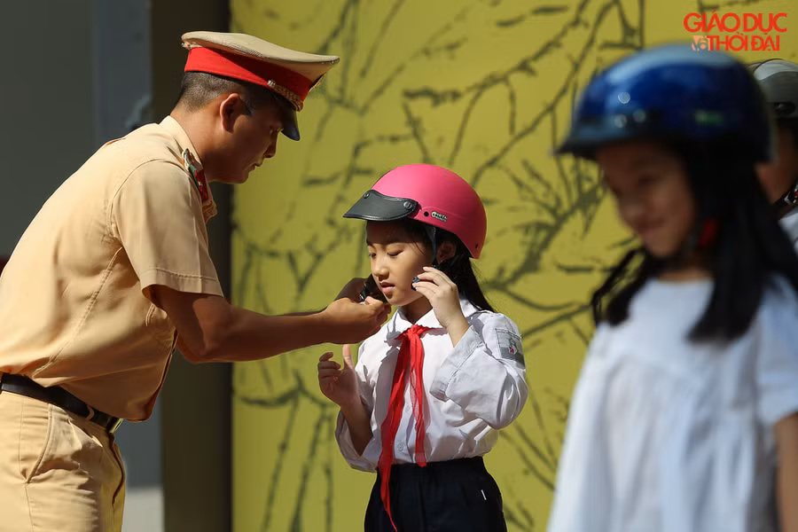 Học sinh tiểu học được hướng dẫn đội mũ bảo hiểm đúng cách để an toàn khi tham gia giao thông.