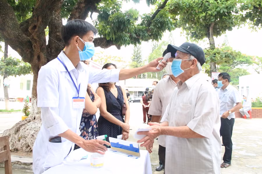 Các cử tri được đo thân nhiệt, sát khuẩn trước khi vào bỏ phiếu.