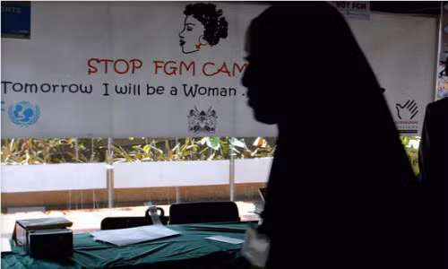 
Một thiếu nữ đi ngang qua biểu ngữ chống cắt bỏ âm vật. Ảnh:AFP.