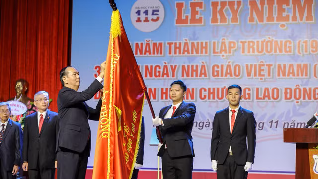 Chủ tịch nước Trần Đại Quang gắn Huân chương Lao động hạng Nhất lên lá cờ truyền thống của trường