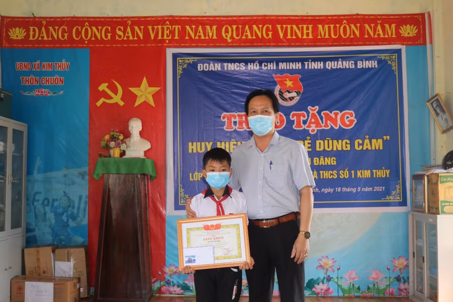Ông Nguyễn Văn Vững – Trưởng phòng GD&amp;ĐT huyện trao Giấy khen của Chủ tịch UBND huyện Lệ Thủy cho em Đăng.