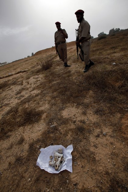 Lực lượng cách mạng ở gần những mẩu xương được tìm thấy Revolutionary fighters stand near bone fragments at the site which is thought to be a possible mass grave near to Abu Salim prison in Tripoli,