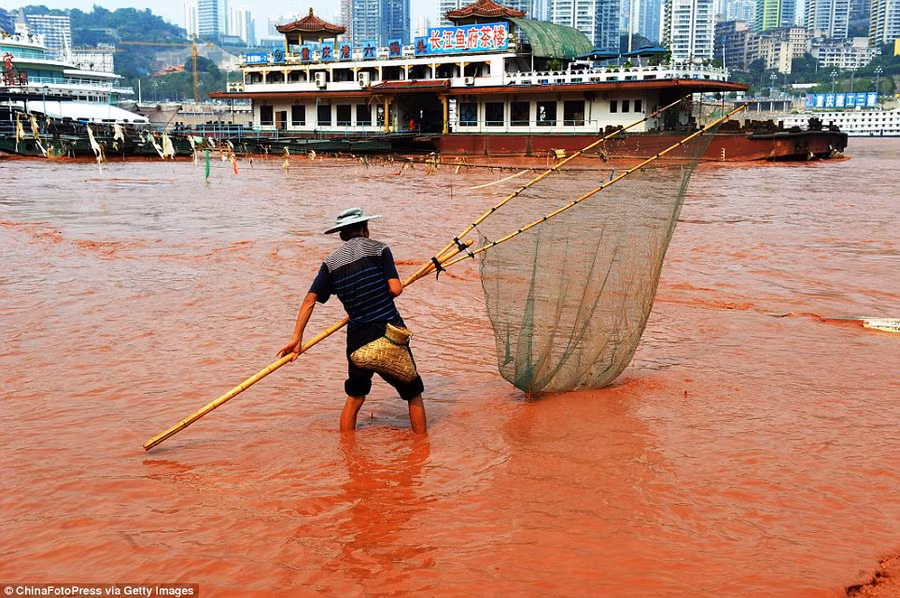 In the thick of it: A fisherman goes about his daily business Read more: http://www.dailymail.co.uk/news/article-2199800/The-river-DID-run-red-Residents-Chinese-city-left-baffled-Yangtze-turns-scarlet.html#ixzz25wdiMFU2
