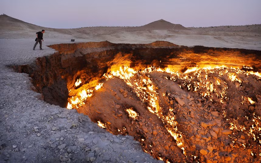 A tourist peers into the Darvaza Gates Of Hell gas crater in the Karakum Desert, Turkmenistan. The eerie cavern has been on fire for more than 40 years. It was discovered in 1971 by Soviet geologists when the ground beneath their drilling rig suddenly collapsed, leaving a large hole with a diameter of 70 metres (230 ft). As the huge crater was filled with potentially poisonous natural gas the decision was made to set it alight. Scientists expected it to burn itself out within a few days, but the fire is still as fierce as ever.