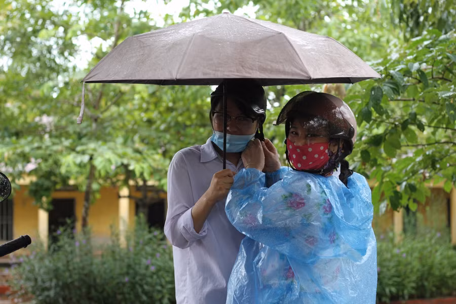 Hai mẹ con một thí sinh nán lại sau khi hoàn thành buổi thi vì cơn mưa nặng hạt.