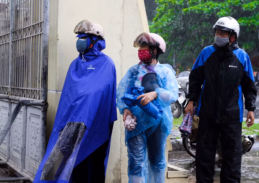 3 vị phụ huynh "đội mưa", hướng ánh mắt tìm kiếm con em mình. Hình ảnh ghi lại sau khi kết thúc các môn thi buổi sáng ngày 8/7.