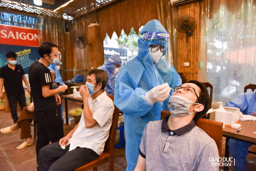 Người dân trước khi vào tiêm vắc xin sẽ được test Covid-19, sau khi có kết quả âm tính sẽ cầm giấy kết quả để tiến hành làm thủ tục tiêm vắc xin.