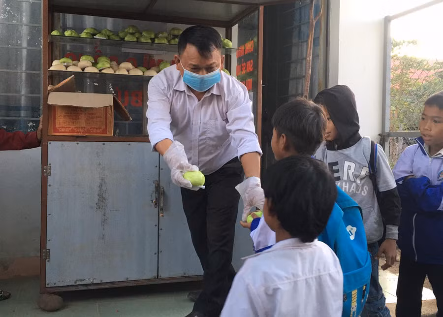 Thầy Tùng phát bánh mì cho học sinh.