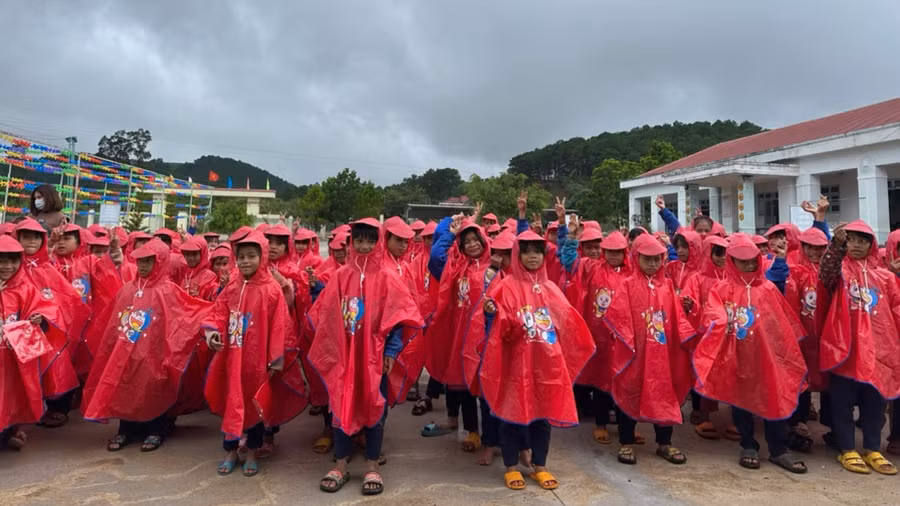 Học sinh thích thú khi nhận được áo mưa mới.