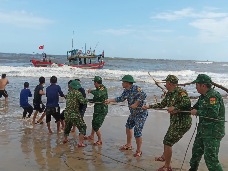 Các cán bộ, chiến sĩ biên phòng phối hợp người dân cứu hộ tàu mắc cạn.