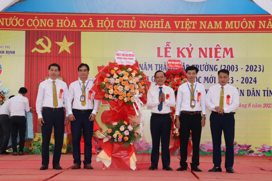 Ông Trần Xuân Anh, Bí thư Huyện ủy Triệu Phong (thứ 3, bên phải) tặng hoa chúc mừng nhà trường nhân kỷ niệm 20 năm thành lập.