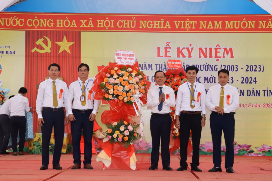 Ông Trần Xuân Anh, Bí thư Huyện ủy Triệu Phong (thứ 3, bên phải) tặng hoa chúc mừng nhà trường nhân kỷ niệm 20 năm thành lập.