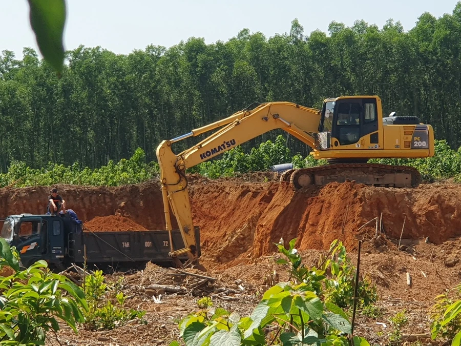 Máy xúc hoạt động liên tục để lấy đất chất lên xe tải chở ra ngoài.