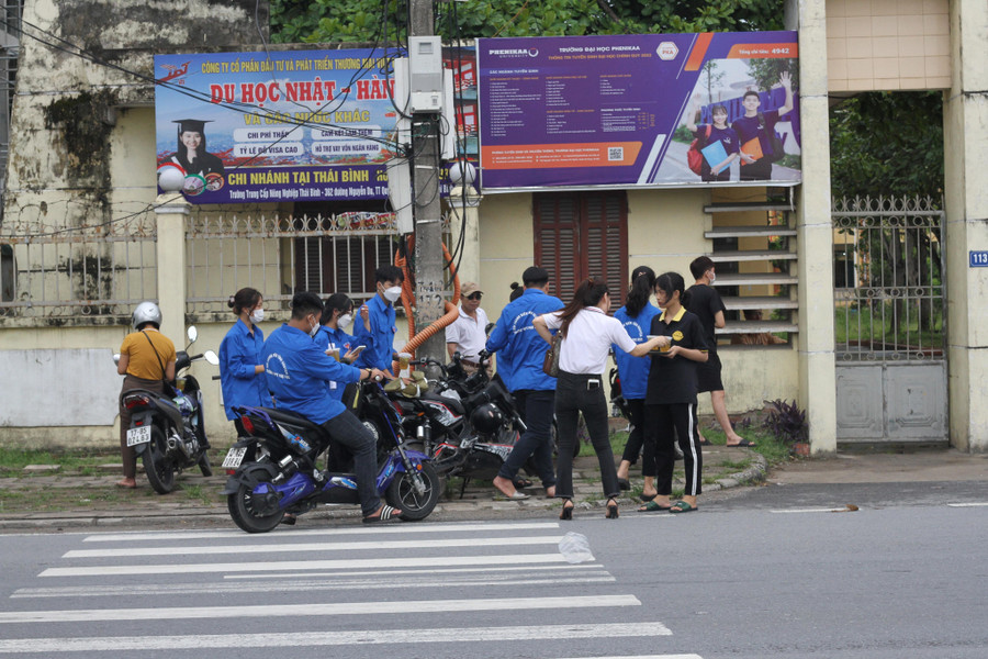 Các thành viên trong nhóm của anh Hùng trao những cốc trà chanh miễn phí tới lực lượng tình nguyện tại điểm thi trường THPT Phụ Dực.